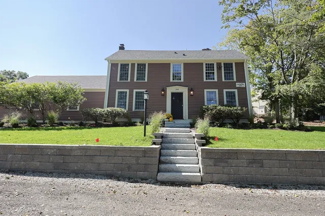 a front view of a house with a yard and a large tree