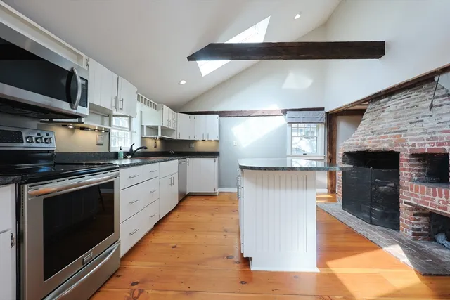 a kitchen with stainless steel appliances granite countertop a stove a sink and a microwave