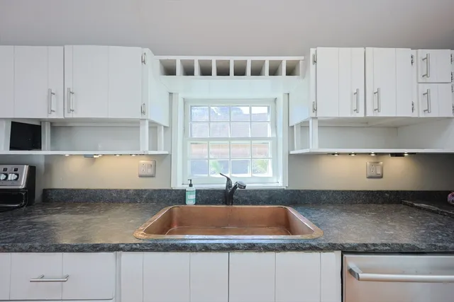 a kitchen with granite countertop a sink a window and cabinets