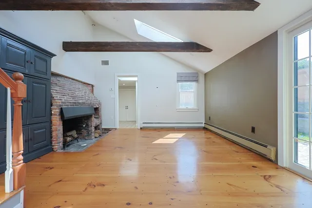 a view of empty room with wooden floor and fireplace