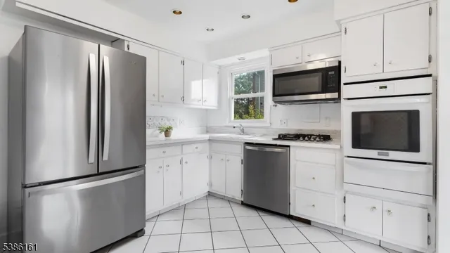 a kitchen with white cabinets white stainless steel appliances and sink