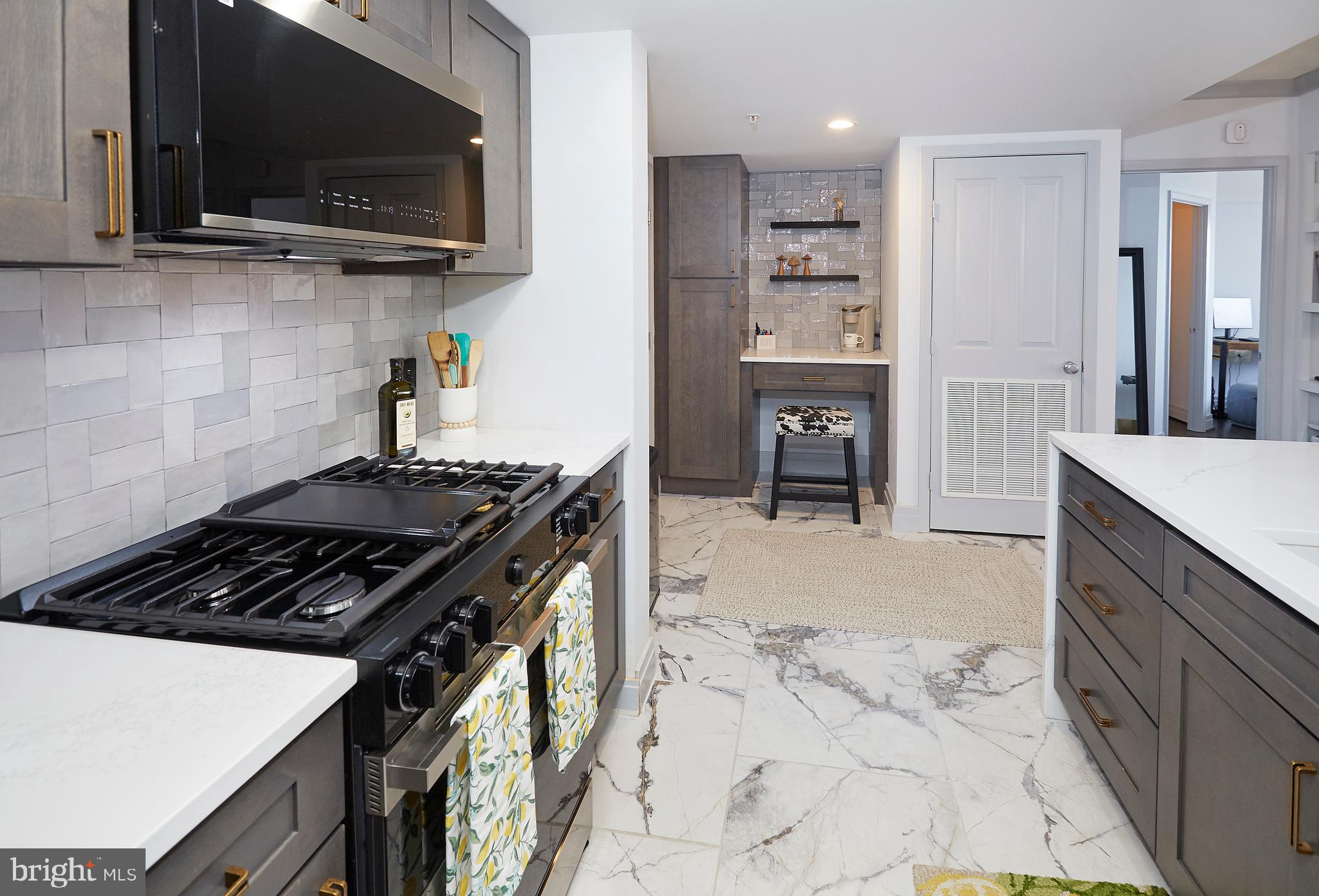 414 Water Street, Unit 2601 Baltimore, MD 21202 - Photo 9 of 51 a kitchen with stainless steel appliances a stove a microwave and wooden cabinets