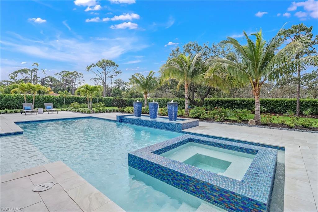 12 Banyan Road Naples, FL 34108 - Photo 41 of 44 a view of a swimming pool with a lawn chairs under an umbrella