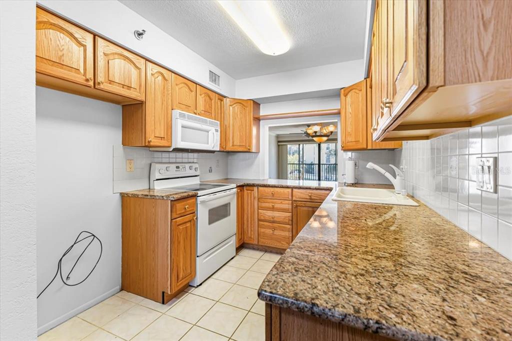 53 West Bay Heights Road, Unit 205 Englewood, FL 34223 - Photo 20 of 43 a kitchen with stainless steel appliances granite countertop a stove a sink and a microwave