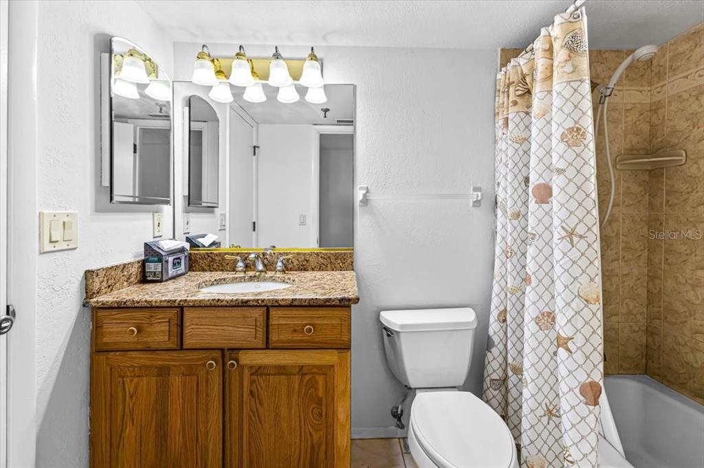 53 West Bay Heights Road, Unit 205 Englewood, FL 34223 - Photo 28 of 43 a bathroom with a granite countertop toilet sink and mirror