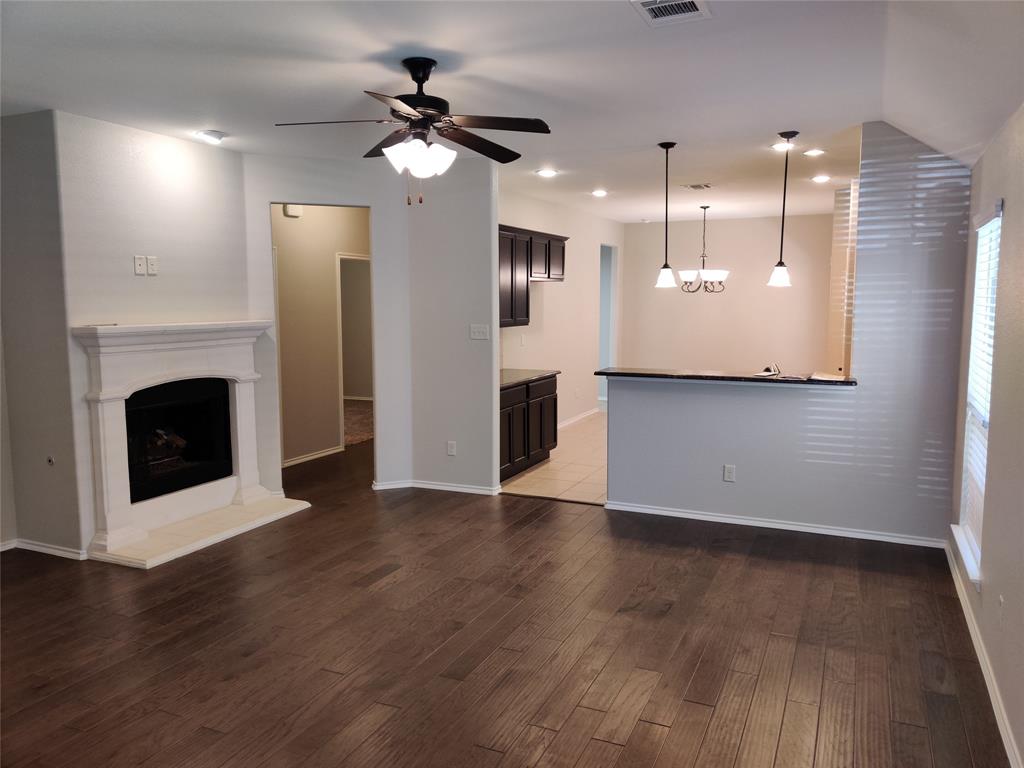 9901 Pronghorn Road McKinney, TX 75071 - Photo 4 of 27 a view of a livingroom with a fireplace a ceiling fan and wooden floor
