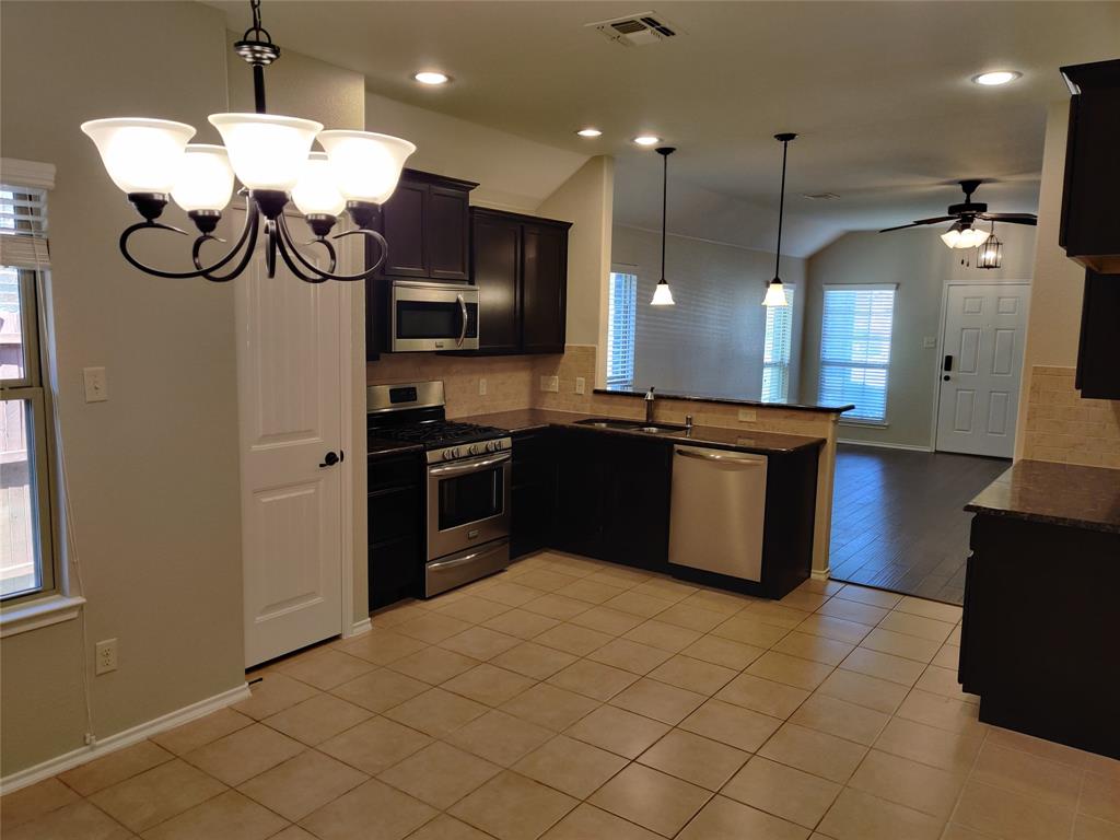 9901 Pronghorn Road McKinney, TX 75071 - Photo 6 of 27 a kitchen with kitchen island granite countertop a sink cabinets and stainless steel appliances