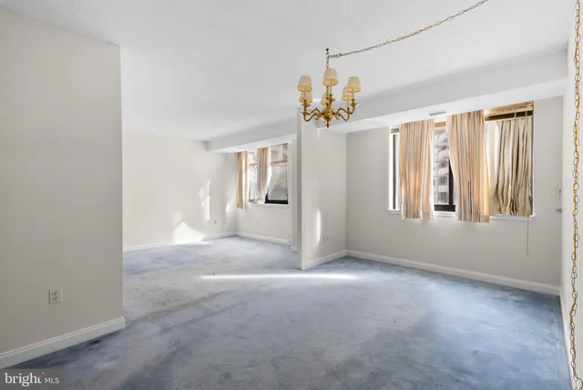 an empty room with windows and chandelier