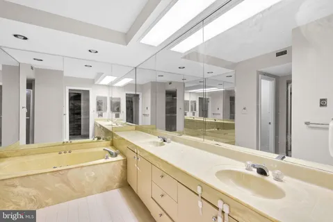 a bathroom with a granite countertop tub sink and mirror