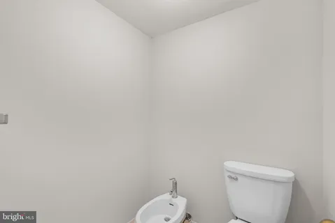 a white toilet sitting next to a white wall