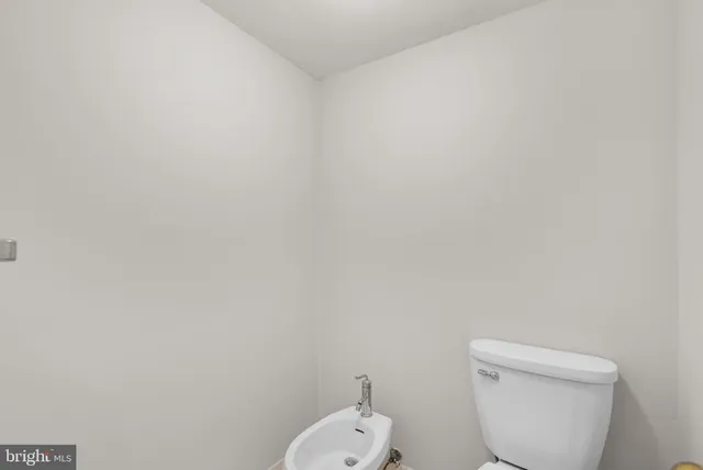 a white toilet sitting next to a white wall