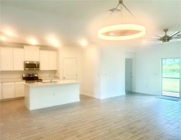 a view of kitchen and empty room with wooden floor