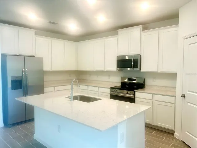 a kitchen with a sink a stove a refrigerator and cabinets
