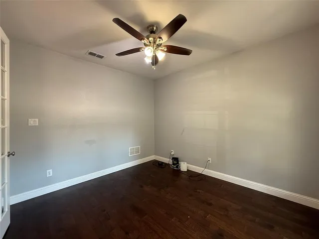 an empty room with wooden floor and a ceiling fan