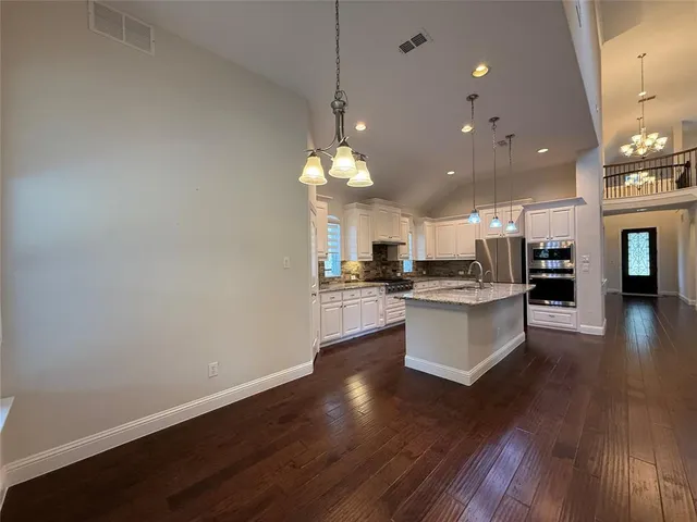 a kitchen with stainless steel appliances kitchen island wooden floors and white cabinets