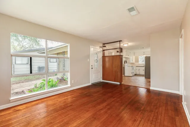 a view of empty room with wooden floor and a window