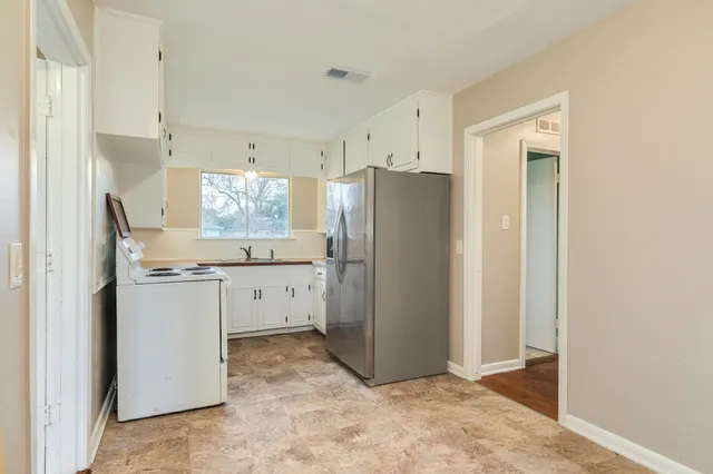 a kitchen with a refrigerator and white cabinets