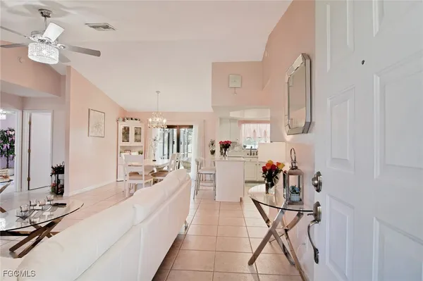 a living room with furniture a chandelier and a view of kitchen