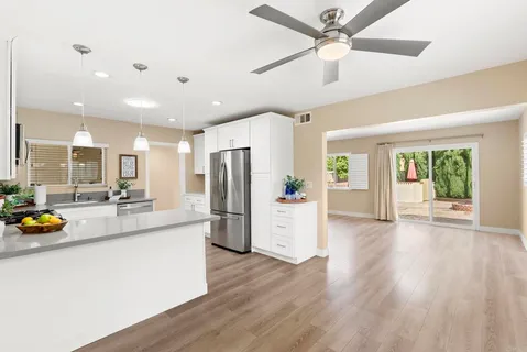 a view of a kitchen with a refrigerator a sink dishwasher a dining table and chairs with wooden floor