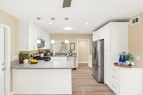 a kitchen with a refrigerator a stove cabinets and living room view