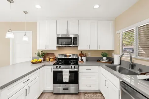 a kitchen with stainless steel appliances granite countertop a sink a stove a microwave a refrigerator a sink and cabinets with wooden floor