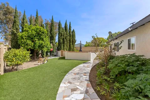a view of a backyard with potted plants and large trees