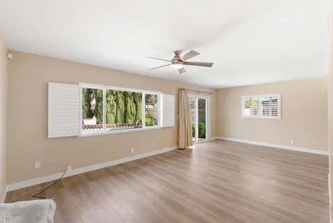 a view of an empty room with a window and wooden floor