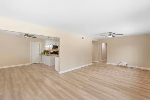 a view of kitchen and empty room with wooden floor