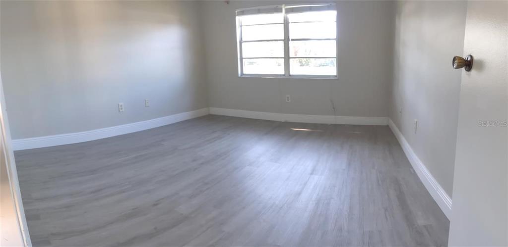 2472 Enterprise Road, Unit 6 Clearwater, FL 33763 - Photo 18 of 22 an empty room with wooden floor and windows