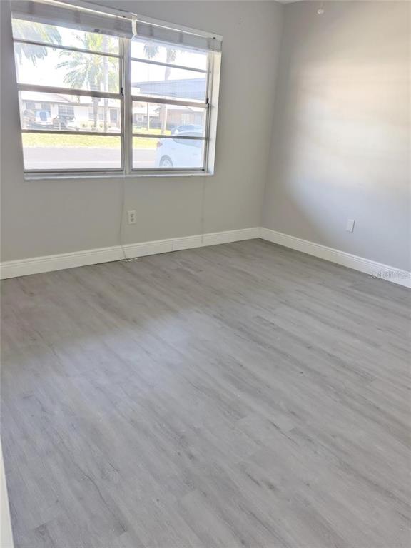 2472 Enterprise Road, Unit 6 Clearwater, FL 33763 - Photo 19 of 22 an empty room with wooden floor and windows