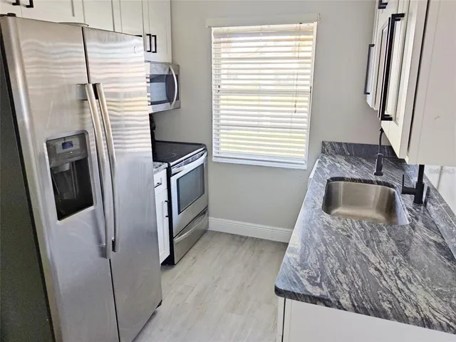 a kitchen with stainless steel appliances granite countertop a refrigerator and a sink