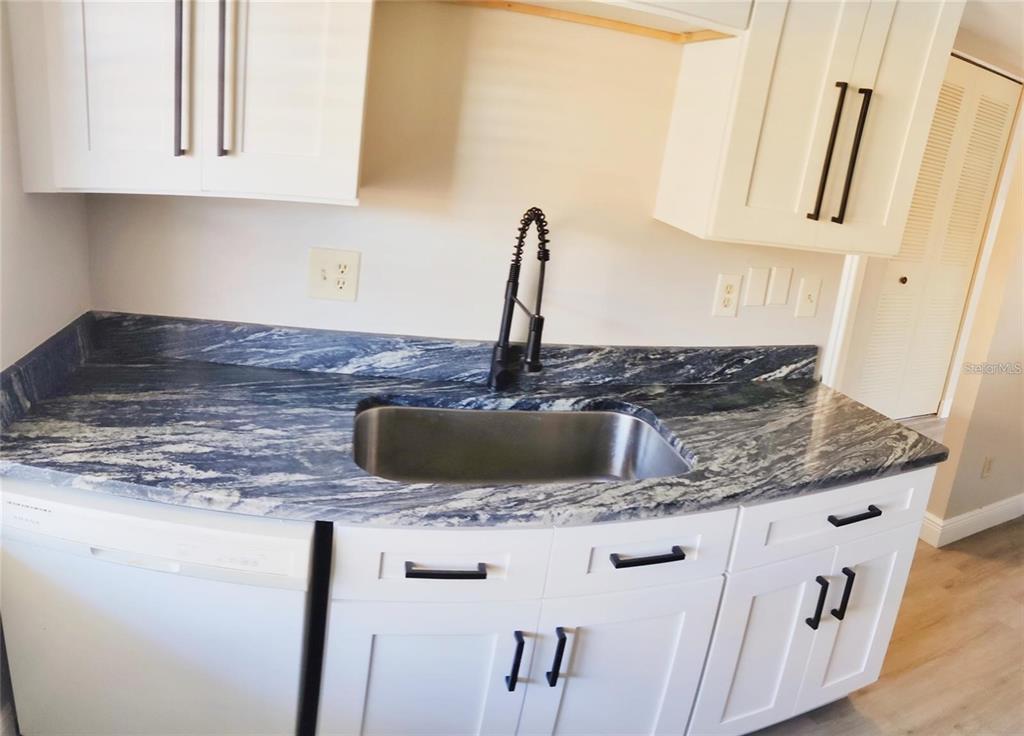 2472 Enterprise Road, Unit 6 Clearwater, FL 33763 - Photo 6 of 22 a kitchen with granite countertop a sink a stove and cabinets