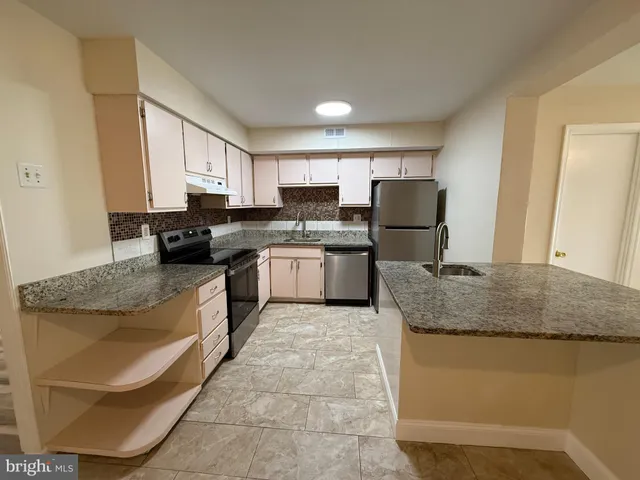 a kitchen with stainless steel appliances granite countertop a sink stove refrigerator and cabinets
