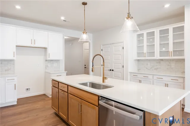 a kitchen with a sink a center island stainless steel appliances and cabinets