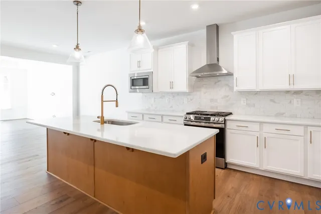 a kitchen with stainless steel appliances granite countertop a sink stove and white cabinets with wooden floor