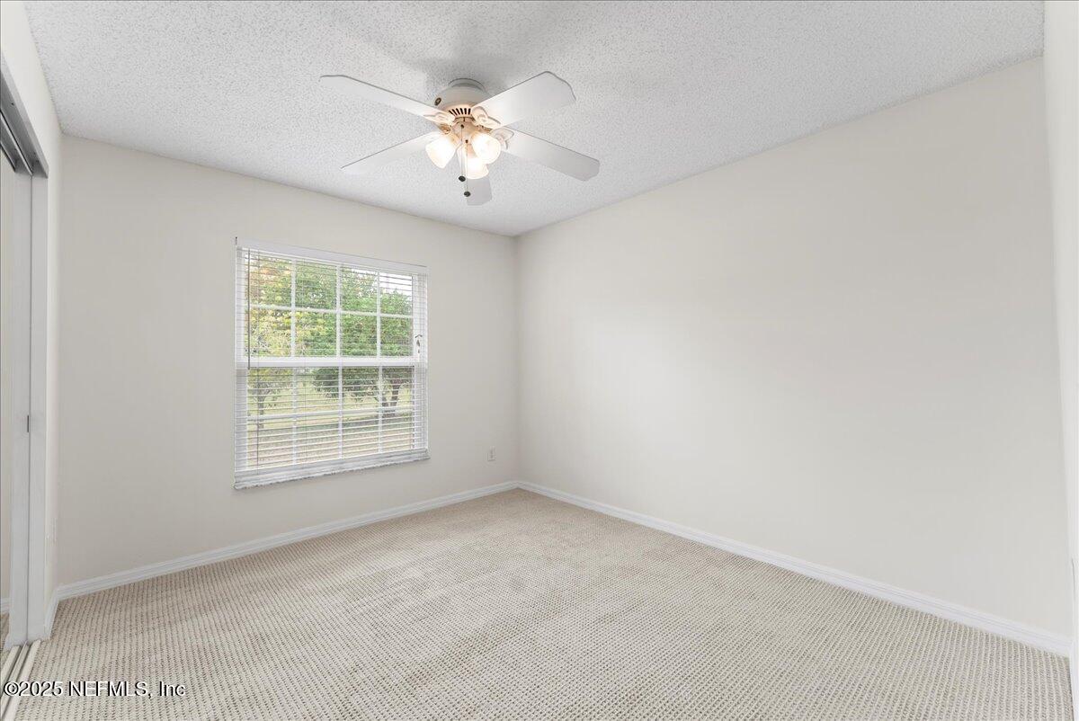 210 Dartmouth Road St. Augustine, FL 32086 - Photo 24 of 27 an empty room with a chandelier fan and windows