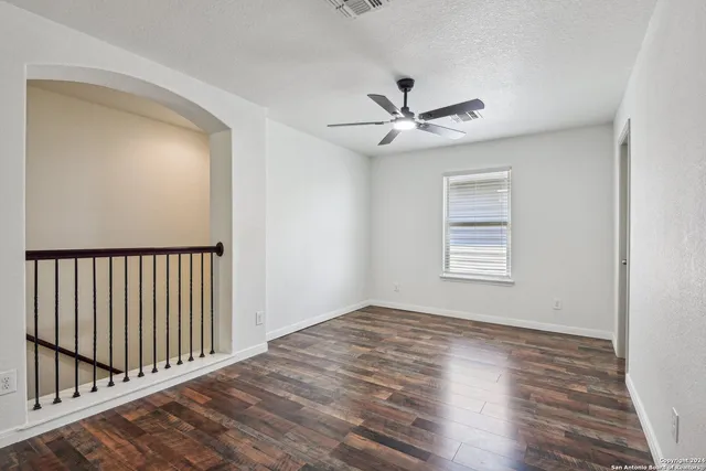 a view of empty room with wooden floor and fan
