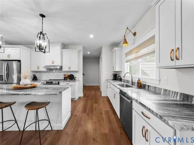 a kitchen with stainless steel appliances granite countertop a sink a stove and a refrigerator