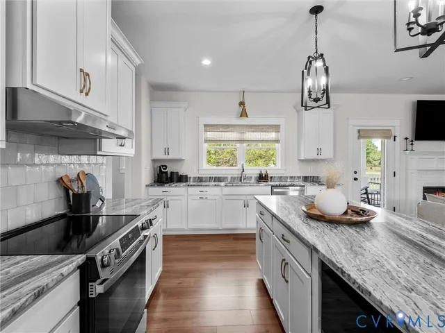 a kitchen with granite countertop kitchen island stainless steel appliances a sink stove and cabinets