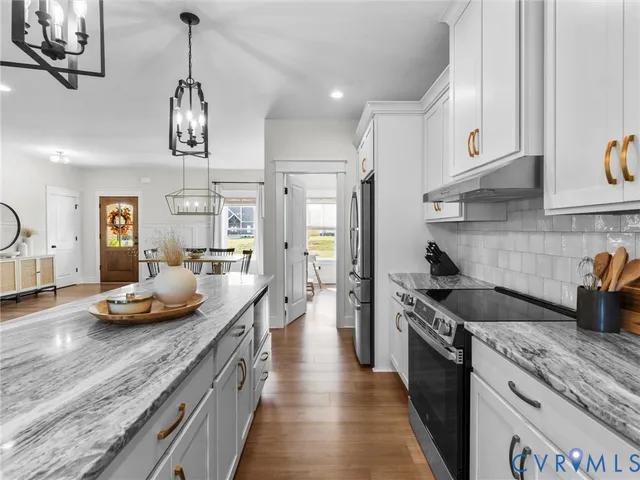 a kitchen with stainless steel appliances granite countertop a sink a stove and a wooden floors