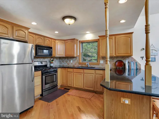 a kitchen with granite countertop a refrigerator a sink a stove and cabinets