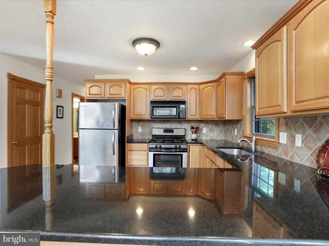 a kitchen with stainless steel appliances granite countertop a stove top oven a sink a dining table and chairs