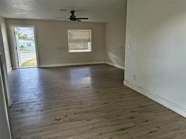 an empty room with wooden floor chandelier and windows