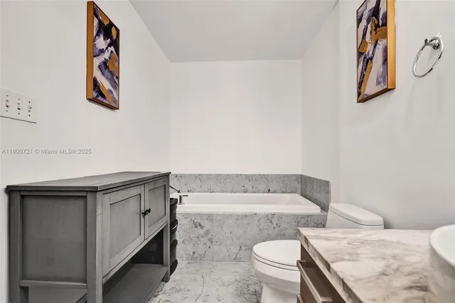a bathroom with a granite countertop toilet and a sink