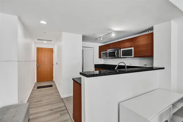 a hallway with stainless steel appliances a stove top oven a sink and a refrigerator