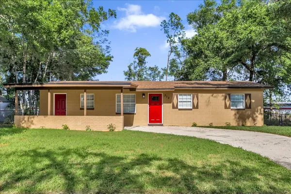 a front view of house with yard and trees in the background