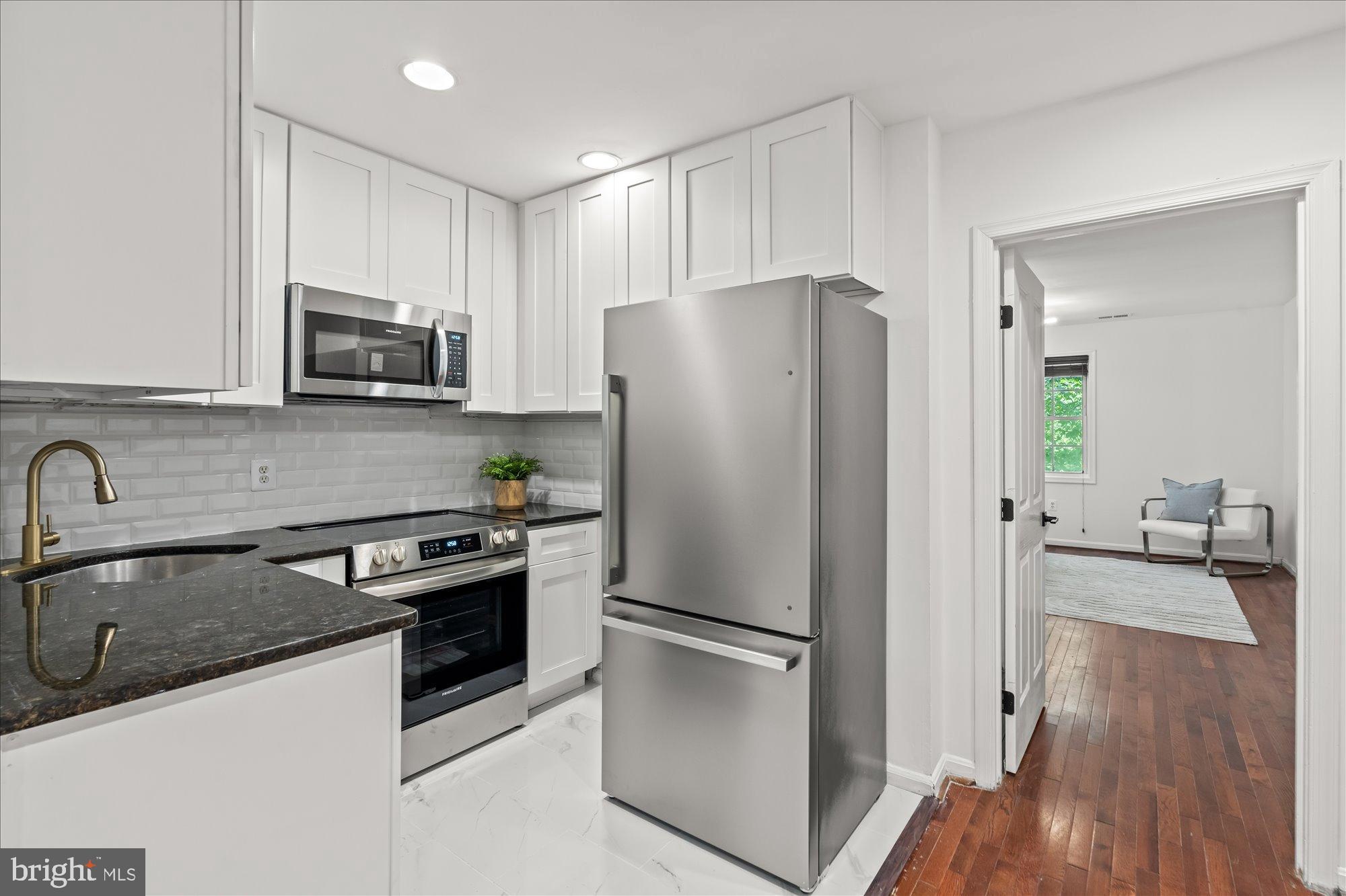 1241 18th Street Northeast, Unit 3 Washington, DC 20002 - Photo 7 of 20 a kitchen with stainless steel appliances a refrigerator a sink a stove a microwave and wooden floor