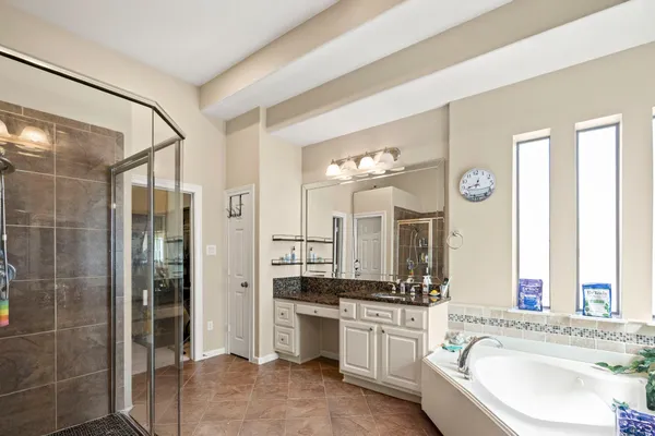 a bathroom with a granite countertop tub sink shower and mirror