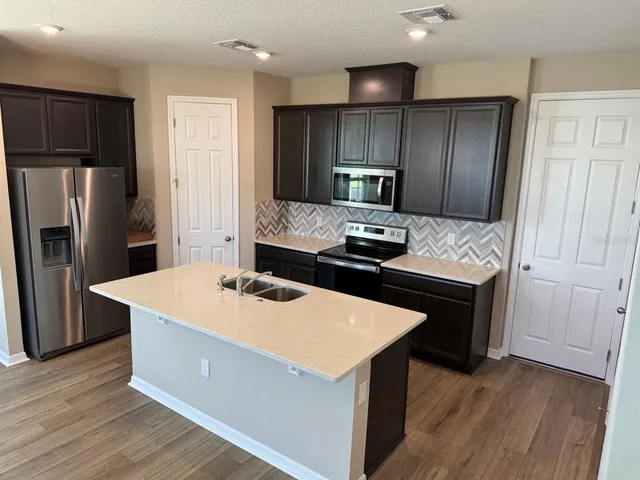 a kitchen with kitchen island a counter appliances a sink and a refrigerator