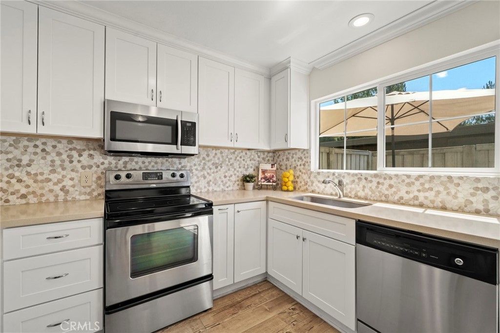 63 Streamwood Irvine, CA 92620 - Photo 13 of 36 Quartz countertops, a designer stone-tile backsplash, custom white shaker-style soft-close cabinetry with contemporary hardware